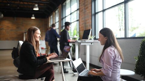 Zwei Frauen sitzen im Büro und unterhalten sich.